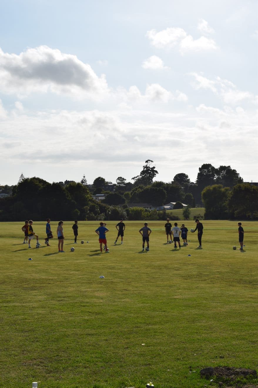 group of players in a field around a football in a training session